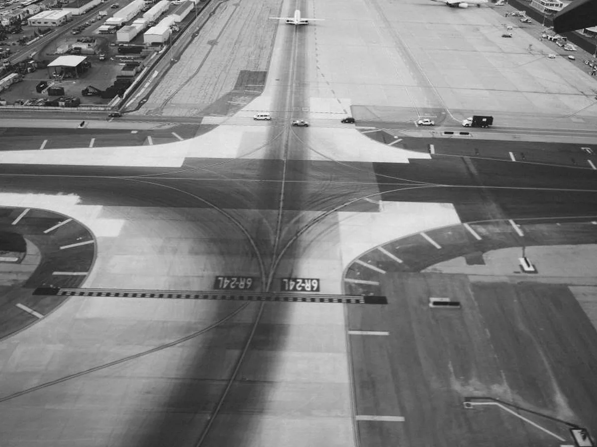 An aerial black-and-white view of an airport runway and taxiways.