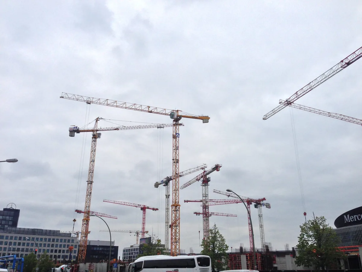 Several tower cranes above a large urban construction site.