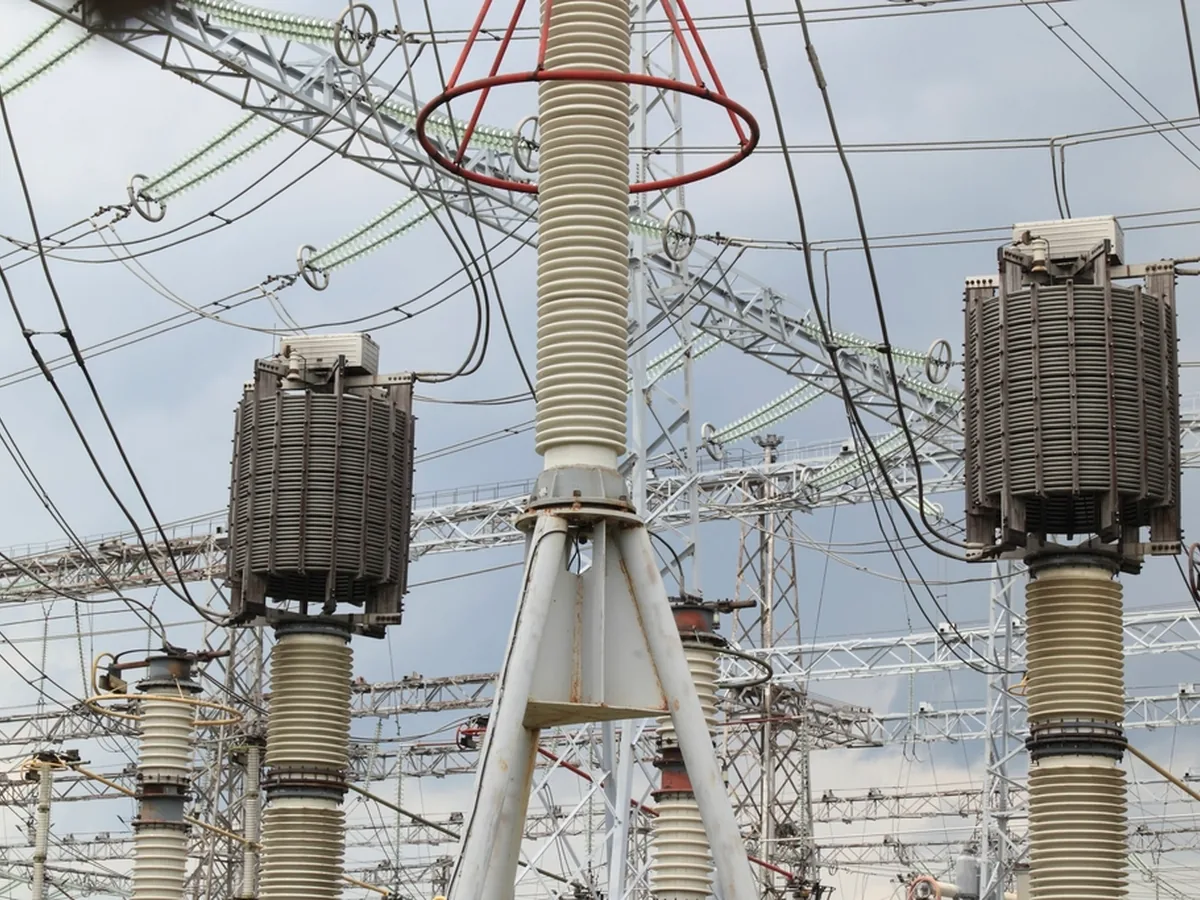 High-voltage transformers and insulators at an electrical substation.