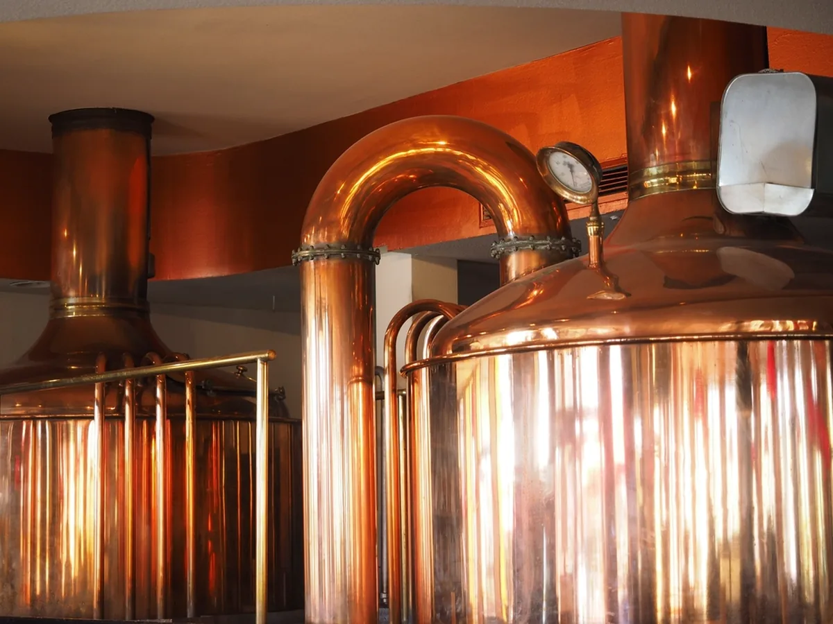 Copper brewing vessels and pipework inside a brewery.