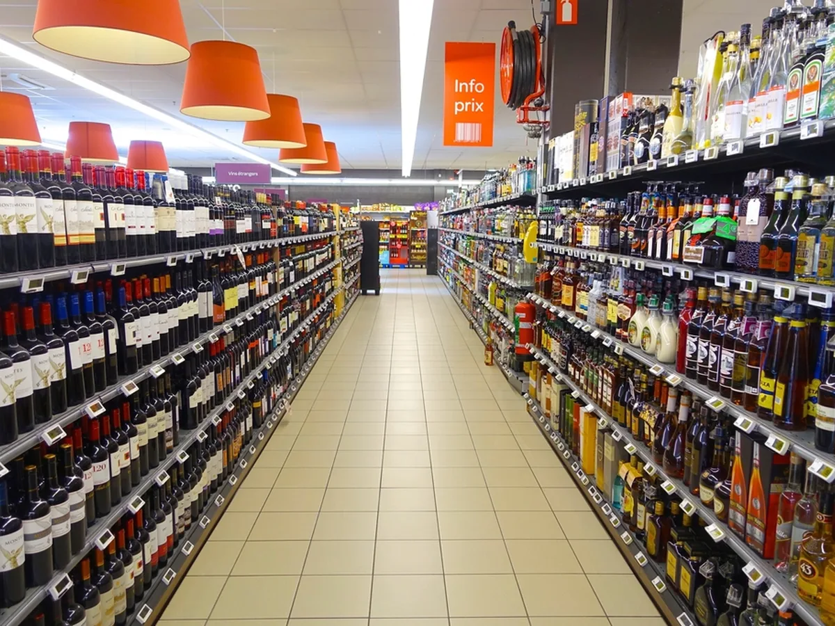 A long supermarket aisle lined with shelves of bottled drinks.
