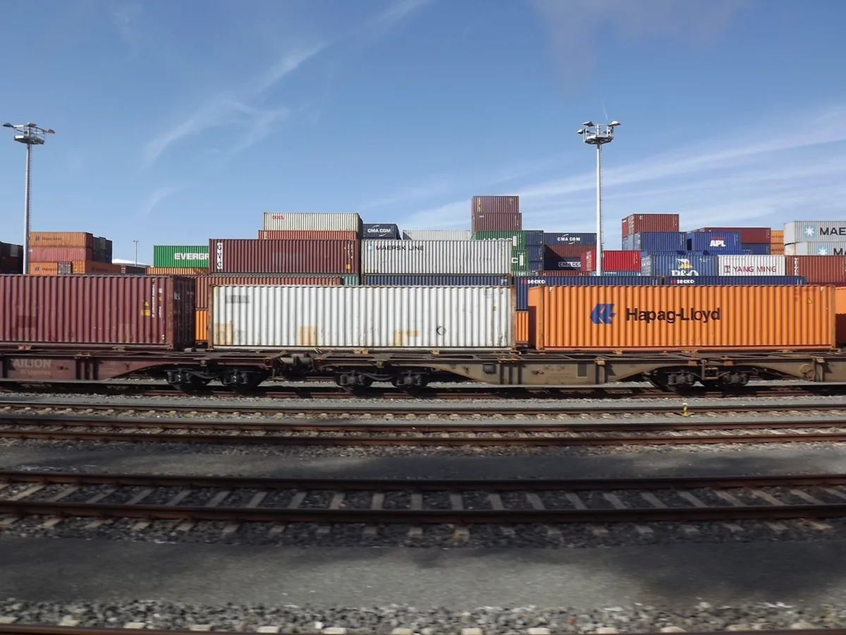 A freight train carrying shipping containers through a rail yard.
