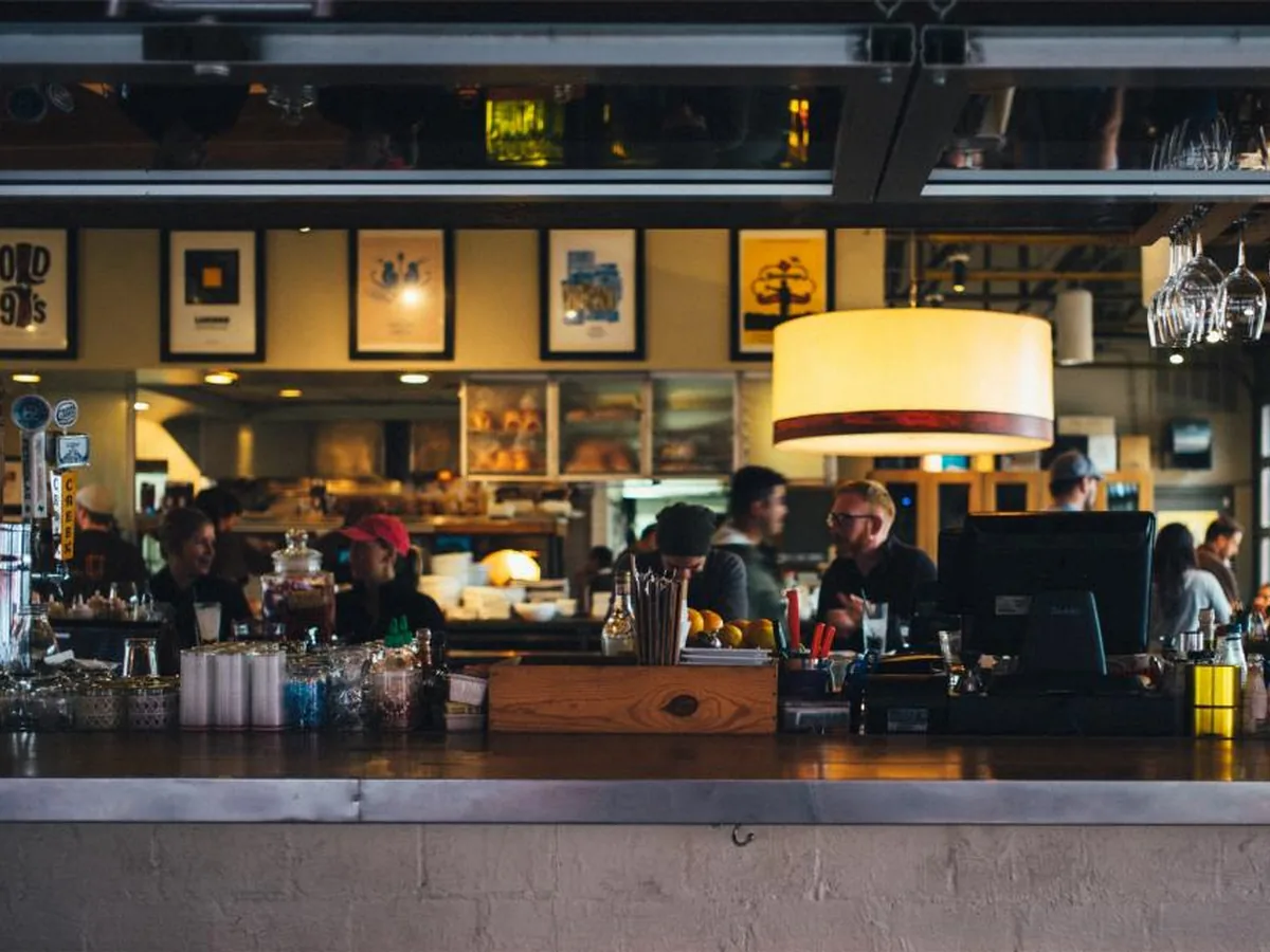 Diners and staff at the counter of a busy restaurant.
