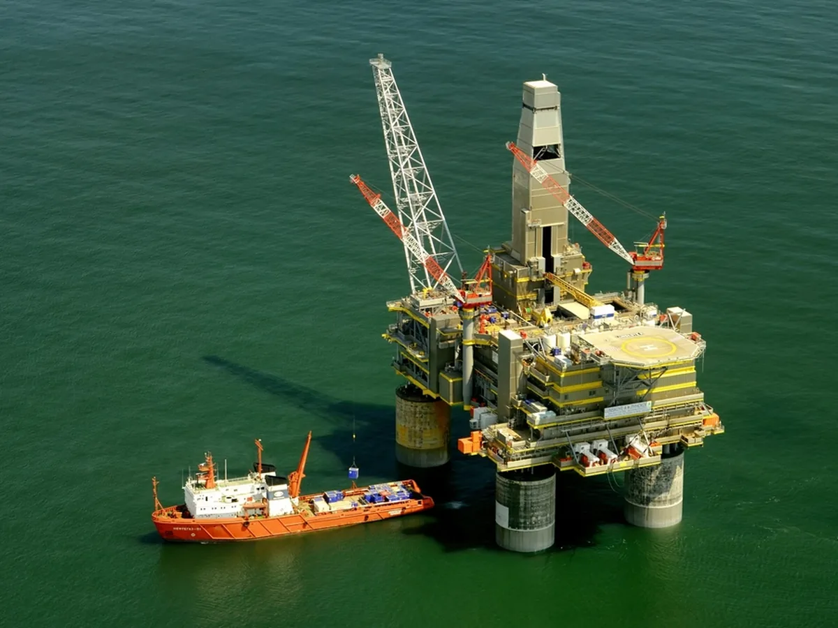 An aerial view of an offshore oil platform with a supply vessel alongside.