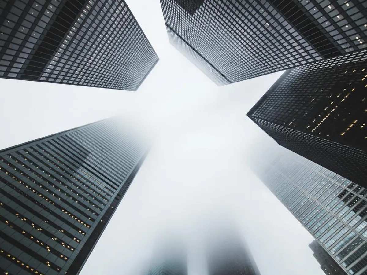Office towers seen from street level rising into the mist.