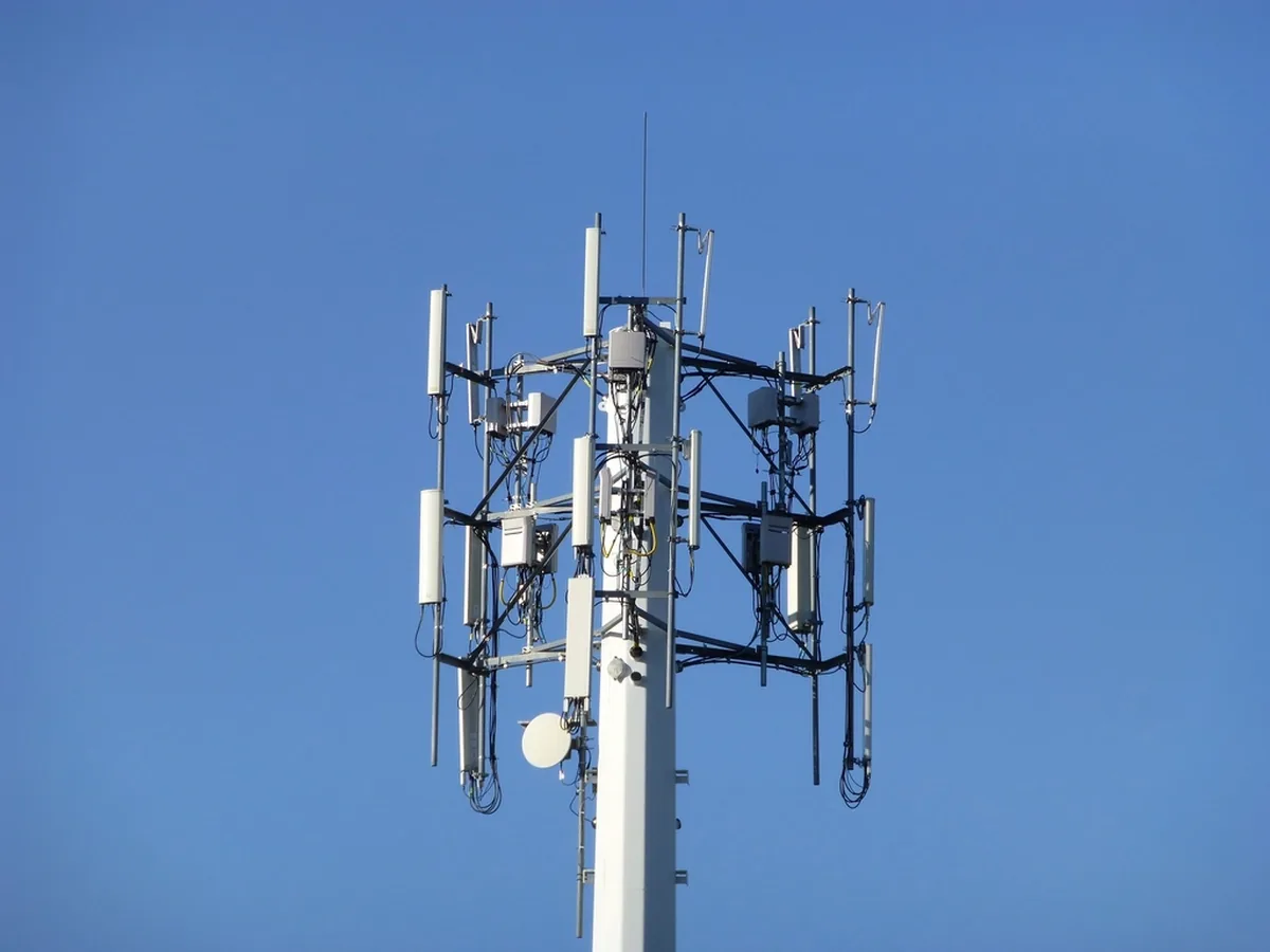A mobile phone mast with antennas against a blue sky.